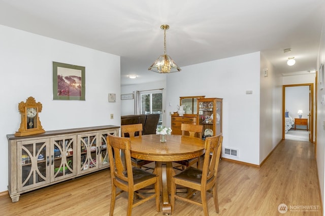 dining area featuring light wood-type flooring, baseboards, visible vents, and a chandelier