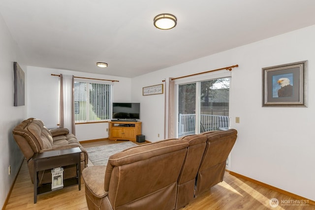 living area featuring a wealth of natural light, light wood-type flooring, and baseboards