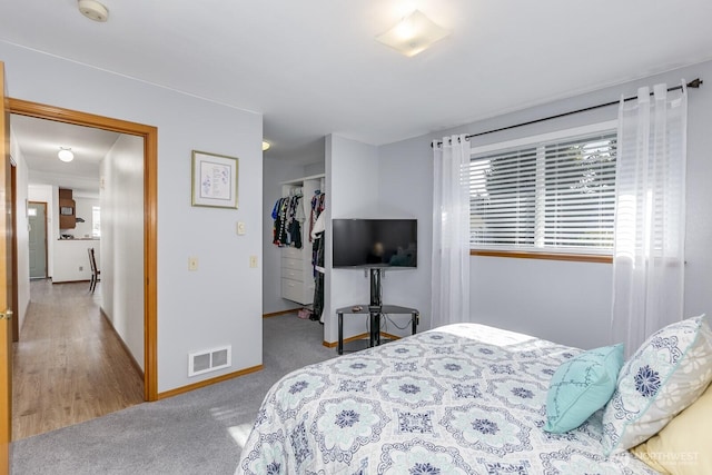 carpeted bedroom featuring baseboards, visible vents, a walk in closet, and a closet