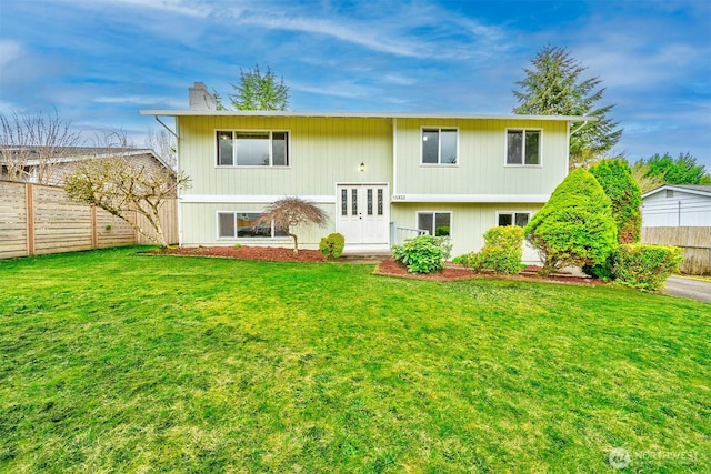 rear view of property featuring a chimney, fence, french doors, and a yard