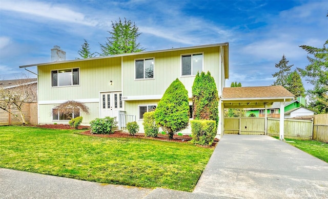 split foyer home featuring concrete driveway, a front lawn, a chimney, and fence