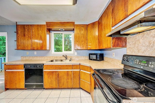 kitchen with brown cabinets, light countertops, a sink, under cabinet range hood, and black appliances