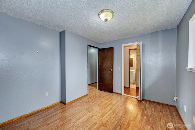 unfurnished bedroom featuring light wood-type flooring, a textured ceiling, and baseboards