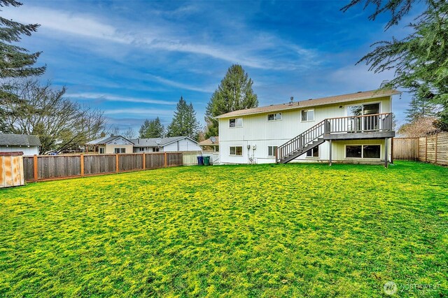 back of property with a fenced backyard, stairway, a lawn, and a wooden deck