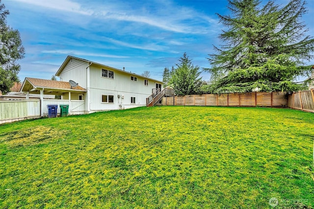 view of yard with a fenced backyard and stairs