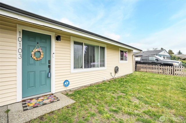 property entrance featuring a lawn and fence