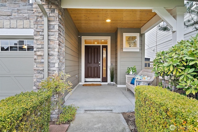 entrance to property featuring stone siding, a porch, and an attached garage