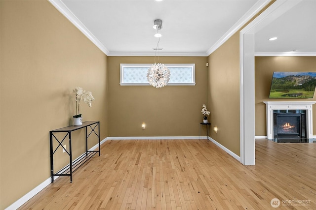 interior space with ornamental molding, a fireplace with flush hearth, light wood-style flooring, and baseboards