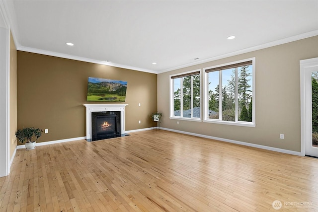 unfurnished living room featuring ornamental molding, baseboards, light wood finished floors, and a fireplace with flush hearth