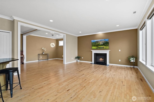 unfurnished living room with light wood finished floors, a fireplace with flush hearth, baseboards, and crown molding