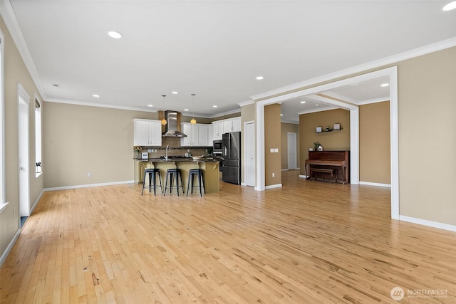 unfurnished living room featuring ornamental molding, light wood finished floors, and baseboards