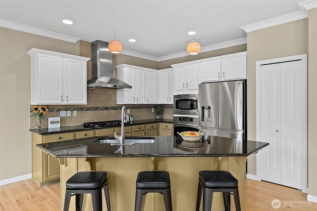 kitchen featuring stainless steel appliances, a sink, wall chimney range hood, and ornamental molding