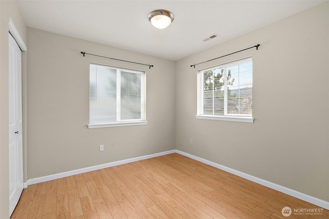 unfurnished room with light wood finished floors, visible vents, and baseboards