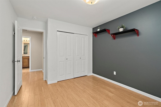 unfurnished bedroom with a closet, light wood-type flooring, and baseboards