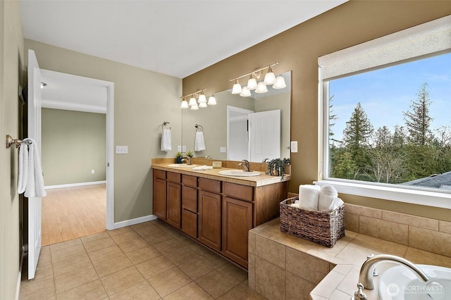 full bath featuring tile patterned flooring, a sink, baseboards, and double vanity