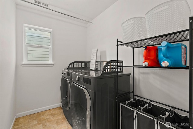 washroom with laundry area, visible vents, baseboards, and washer and clothes dryer