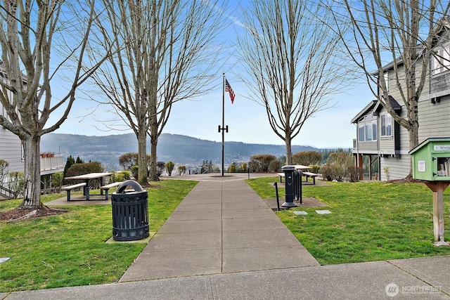 surrounding community with a mountain view and a lawn