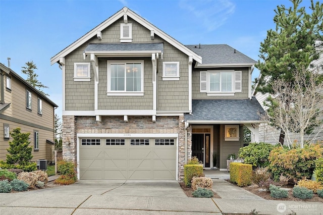 craftsman-style house featuring stone siding, a shingled roof, an attached garage, and driveway