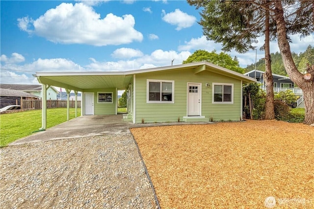 view of front of property featuring fence, an attached carport, concrete driveway, and a front yard