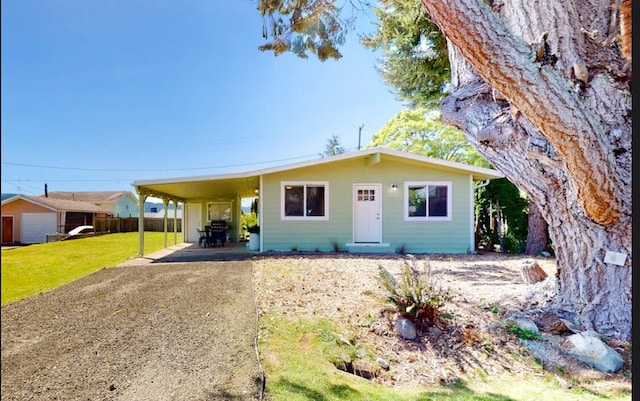 view of front facade featuring driveway, an attached carport, and a front yard