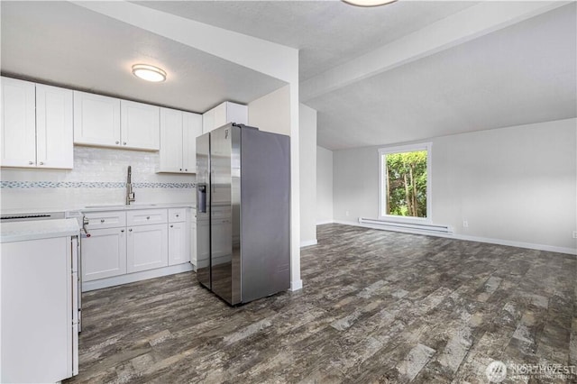 kitchen with stainless steel fridge, open floor plan, vaulted ceiling with beams, a baseboard heating unit, and a sink