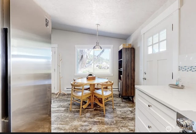 dining area featuring lofted ceiling, a baseboard heating unit, and a textured ceiling