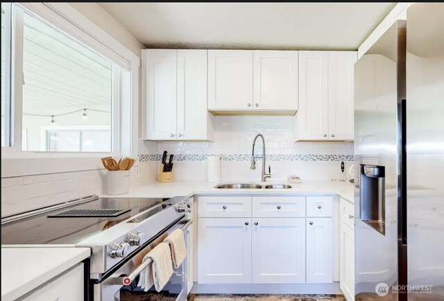 kitchen with light countertops, appliances with stainless steel finishes, a sink, and white cabinetry