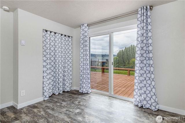 unfurnished room featuring a textured ceiling, wood finished floors, and baseboards