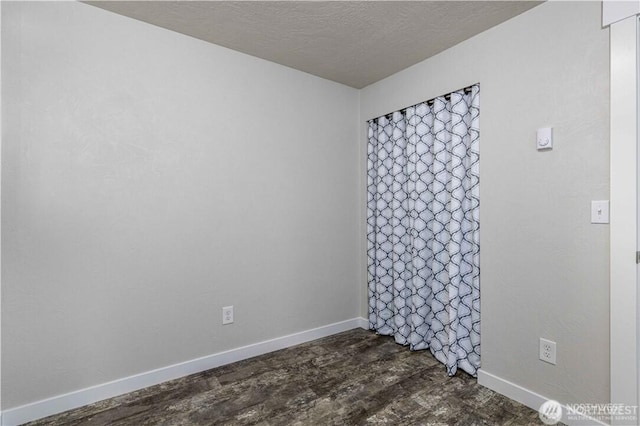 spare room with a textured ceiling and baseboards