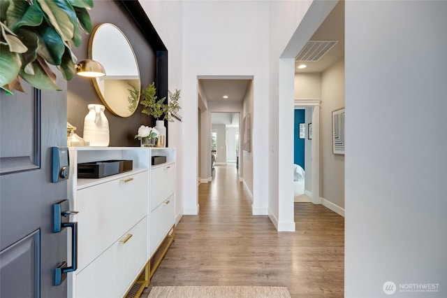 hall with light wood-style flooring, visible vents, baseboards, and recessed lighting