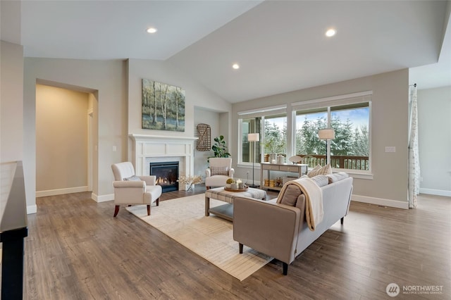 living area featuring lofted ceiling, recessed lighting, baseboards, a glass covered fireplace, and wood finished floors