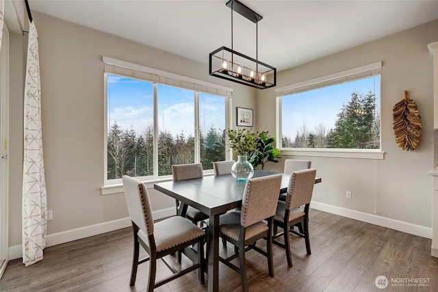 dining space with dark wood-style flooring, plenty of natural light, baseboards, and a chandelier