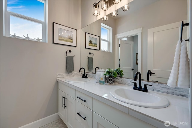 bathroom with baseboards, double vanity, and a sink