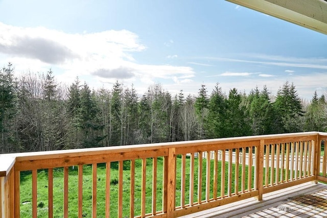 wooden deck featuring a forest view and a lawn