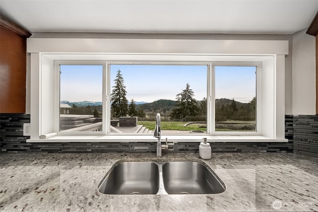 interior details featuring a sink, a mountain view, and light stone counters