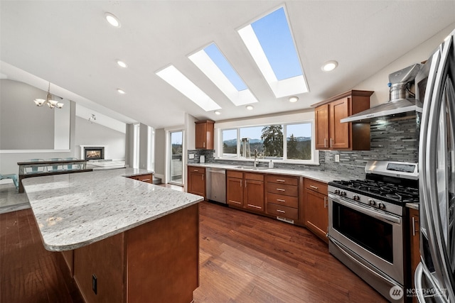 kitchen featuring brown cabinetry, lofted ceiling, dark wood-style flooring, a sink, and stainless steel appliances