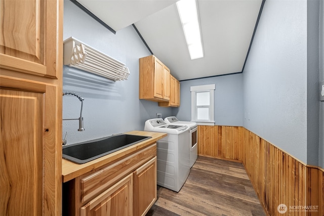 laundry room with dark wood finished floors, cabinet space, a sink, wainscoting, and washer and dryer