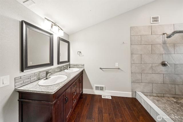 full bathroom with double vanity, wood finished floors, visible vents, and a sink