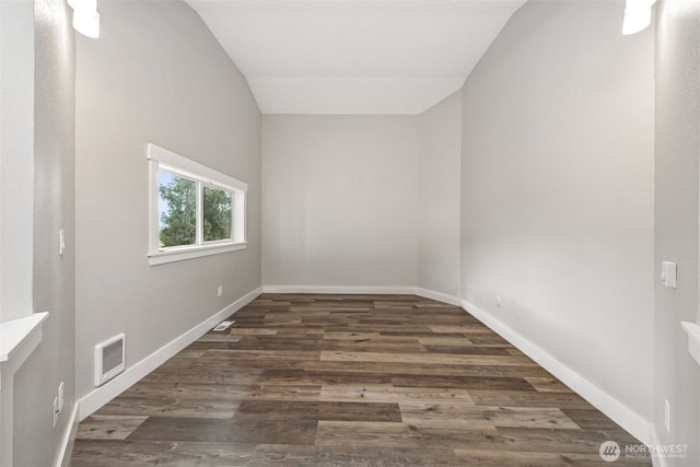 spare room with visible vents, lofted ceiling, baseboards, and wood finished floors