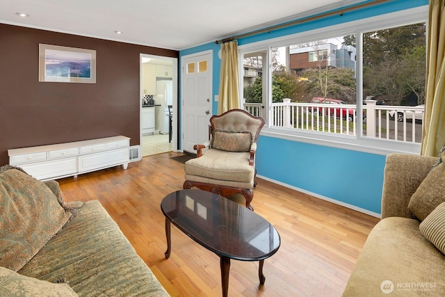 living area with wood finished floors, visible vents, and baseboards