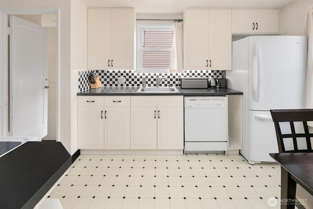 kitchen featuring dark countertops, white appliances, a sink, and backsplash