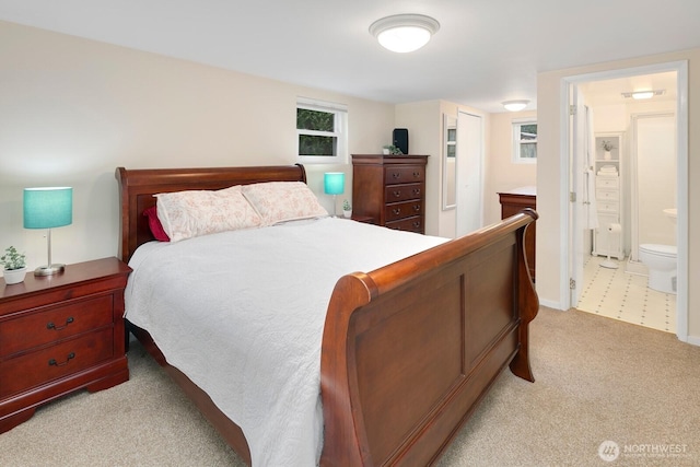 bedroom featuring light carpet and connected bathroom