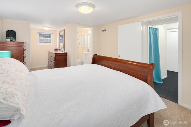 carpeted bedroom with baseboards, visible vents, and ensuite bath