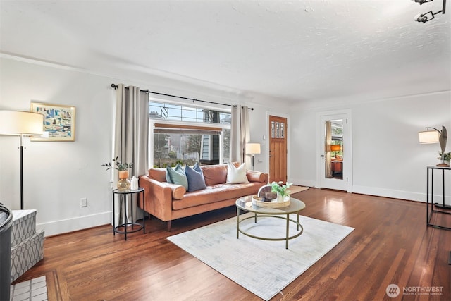 living area with a textured ceiling, wood finished floors, a wealth of natural light, and baseboards