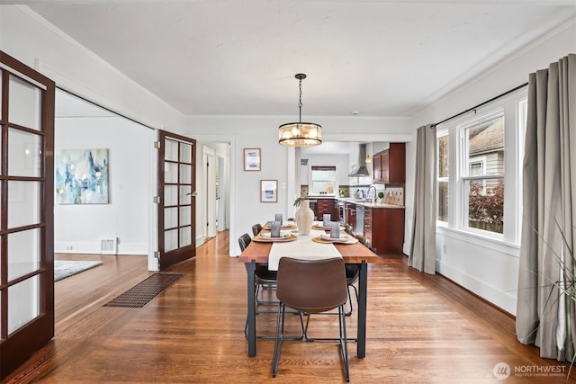 dining room with baseboards, visible vents, ornamental molding, wood finished floors, and french doors