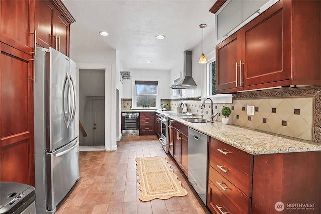 kitchen with appliances with stainless steel finishes, reddish brown cabinets, a sink, and wall chimney exhaust hood