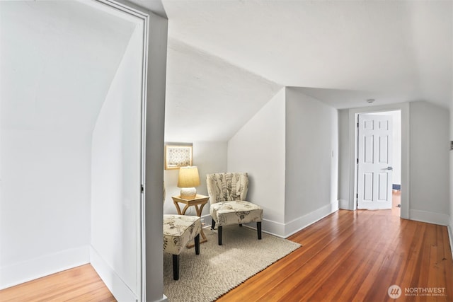 living area with vaulted ceiling, baseboards, and wood finished floors