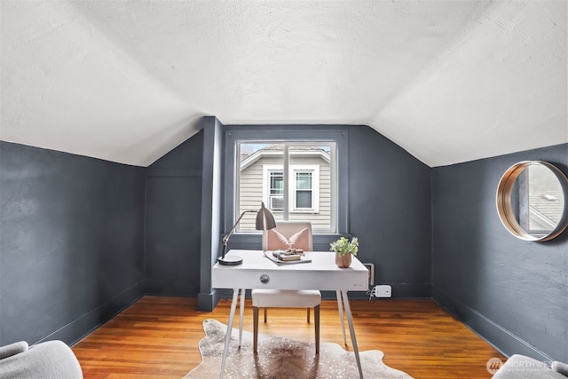 office space with a textured ceiling, baseboards, vaulted ceiling, and wood finished floors