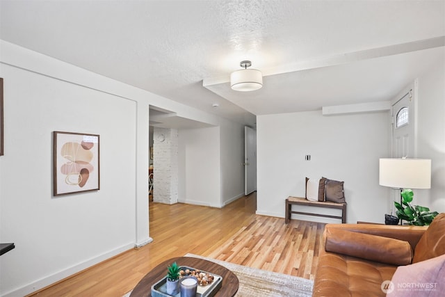 living room featuring a textured ceiling, wood finished floors, and baseboards