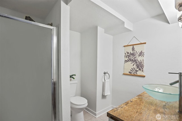 bathroom featuring toilet, a sink, baseboards, tile patterned floors, and a stall shower